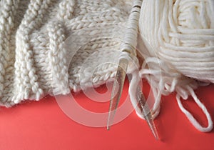 White wool knitting needles and handmade knits on bright orange background