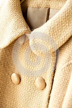 White wool short coat hanging on clothes hanger on white background