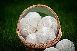 White woolen yarn in basket on green background