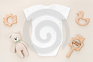 White wrap bodysuit for baby mocap. Mockup of children`s clothes on a pastel brown background with kid`s toys and accessories.
