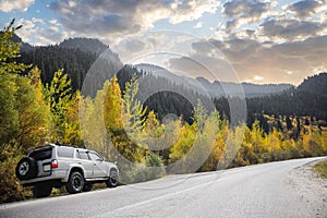 White 4x4 car traveling along a autumn mountains road