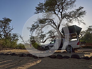 white 4x4 pickup with canopy and roof top tent on road trip