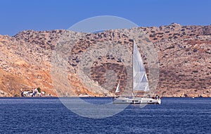 White yacht against the backdrop of high mountains in the bay of Symi island