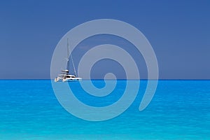 White yacht anchored in fantastic Myrtos Beach turquoise and blue bay. Summer scenery of famous and extremely popular