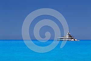 White yacht anchored in fantastic Myrtos Beach turquoise and blue bay. Summer scenery of famous and extremely popular