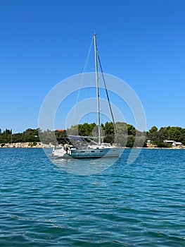 White yacht in the bay of the Adriatic Sea. Holidays on the open sea on a small boat. Boat with a sail near the sea coast