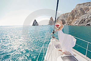 White yacht with sail set goes along the island on a hot day. blue sea, blue sky. Crimea. on board a young couple in