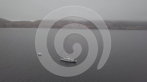White yacht standing on anchor in blue sea on mountain landscape aerial view