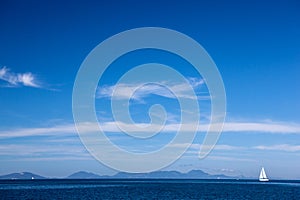 White yacht traveling at sea against a blue sky