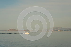 A white yaht near the rocky coastline of Crete, Greece.