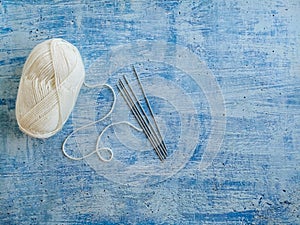 White yarn and knitting needles for knitting socks. Blue rustic background with copy space.