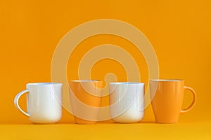 White and yellow coffee cups aligned on yellow background