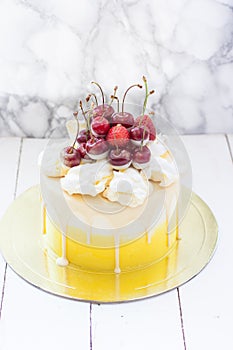 White and yellow colored cake with melted chocolate and fresh cherries on top