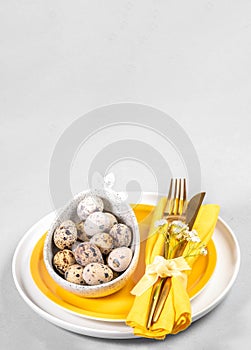 White yellow Easter dishware, quail eggs of natural colors, golden cutlery. Space for menu. Mock up.