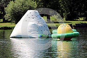White and yellow green inflatable floating climbing walls in different shapes and sizes on calm river surface