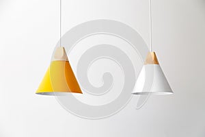 White and yellow lamps with light wooden parts are hanging on the cables