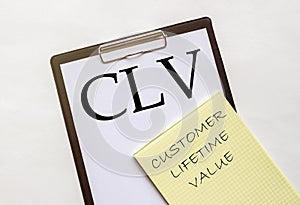 White and yellow paper with text CLV Customer Lifetime Value on a white background with stationery
