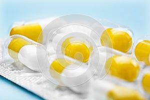 White and yellow pills in a silver plastic packaging