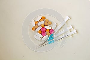 White, yellow and rose tablets pills and three syringes on the table