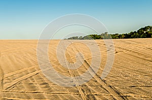 White and yellow sand in the desert with quad bike and car jeep tracks