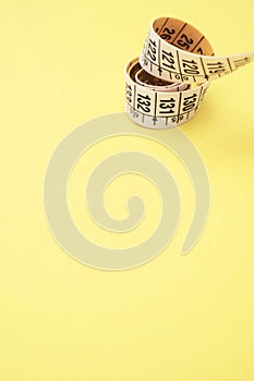 White yellow spiraled measuring tape isolated on a yellow background close up