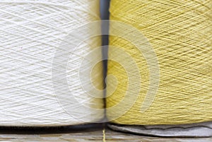 White and yellow yarn on bobbins close up