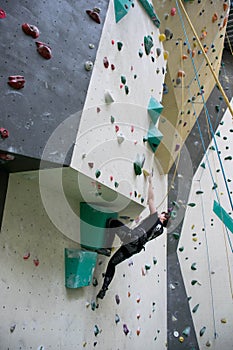 White young adult woman climbing in an indoor climbing gym, active sports. . Slight overhang raching for a hold.