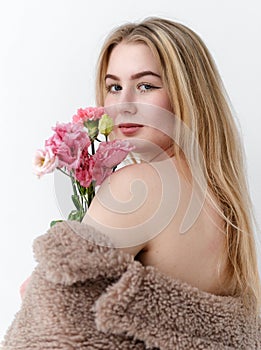 White young blonde woman holds a bouquet of pink flowers with direct look on a white background