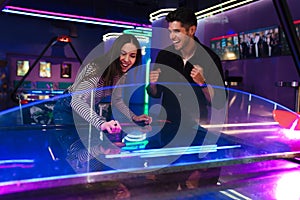 White young friends laughing while playing air hockey
