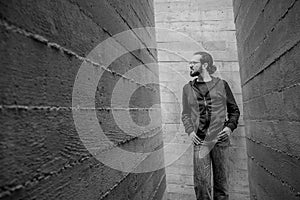 White young handsome man standing near the wall and look up. Portrait of fashion guy in blue jeans and casual wear smiling