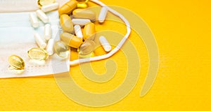 White and yellow pills on  medical mask. intence yellow paper background