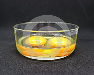 The whites and yolks of two raw eggs in a glass bowl are ready for making an omelet