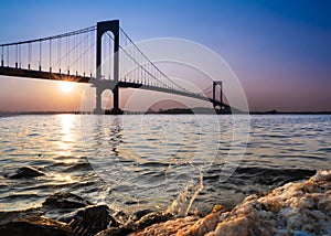 Whitestone Bridge in Queens, New York City at sunset with the water of the Long Island Sound in view.