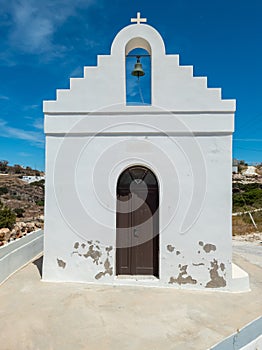 Whitewashed chapel and belfry at Kimolos island Cyclades Greece. Vertical photo