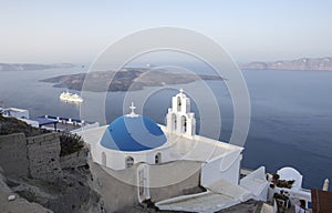 Whitewashed houses and blue dome church by the Aegean sea, Santoriniin Oia, Santorini, Greece. Famous blue domes in Oia village,