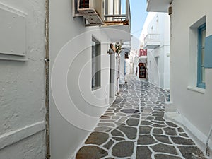 Whitewashed houses empty cobblestone alley at Naousa village, Paros island, Greece