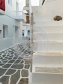 Whitewashed houses empty cobblestone alley at Naousa village, Paros island, Greece. Vertical