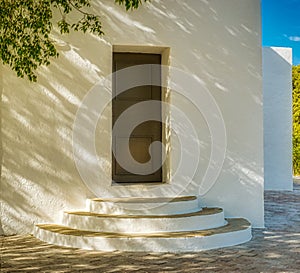 Whitewashed traditional church or hermita in a small village in Spain. Shadows cast over circular steps. Monochrome Diagonal light photo