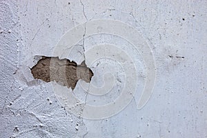 Whitewashed wall with the hole in the cracked plaster