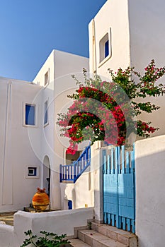 Whitewashed walls of Greek house, blue windows, bougainvillea, blue sky.