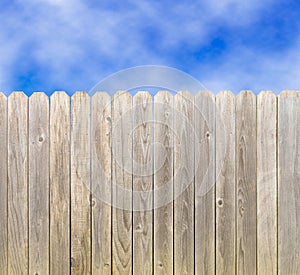 Whitewashed wood privacy fence with blue sky and clouds