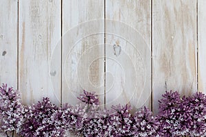 Whitewashed wooden desktop board with beautiful purple lilac flowers at the bottom