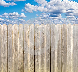 Whitewashed wooden fence with sunny blue sky and clouds
