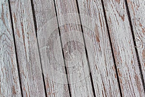 A whitewashed wooden surface worn out due to weather. Planks painted white. The texture of the wooden board