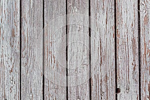 A whitewashed wooden surface worn out due to weather. Planks painted white. The texture of the wooden board