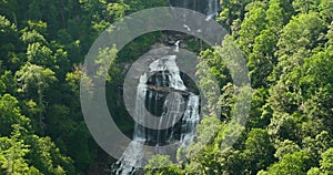 Whitewater Falls with falling down clear water from rocky boulders between green lush woods in Nantahala National Forest