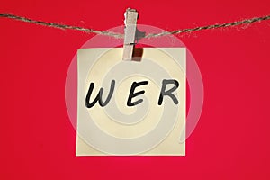 Who, German word for Who, (German: Wer) text on a yellow sticker hanging on a rope with clothespins on a red background