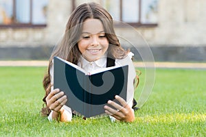 Who needs rest when theres another book to be read. Adorable small child read book on green grass. Cute little girl