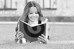 Who needs rest when theres another book to be read. Adorable small child read book on green grass. Cute little girl