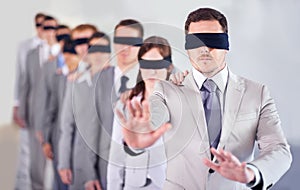 Who shall lead us. a group of blindfolded businesspeople following their manager.